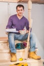 Young contractor sitting on wooden ladder in home Royalty Free Stock Photo
