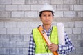 Young contractor stands, ready to work, holds blueprint tape equipment, tape measure Royalty Free Stock Photo