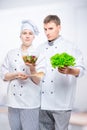 young cooks in suits with salad in hands on gray Royalty Free Stock Photo