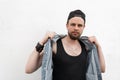 Young cool hipster man in a stylish black cap in a fashionable t-shirt stands near a white wall in the city Royalty Free Stock Photo