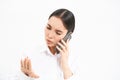 Young corporate employee, woman talks on mobile phone with lack on interest, looks at her nails while listens to person Royalty Free Stock Photo