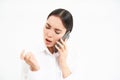 Young corporate employee, woman talks on mobile phone with lack on interest, looks at her nails while listens to person Royalty Free Stock Photo