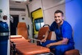 Young corpsman in blue uniform sits in the ambulance car and smiles