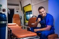 Young corpsman in uniform sits in the ambulance car and smiles