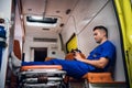 Corpsman in uniform sits with phone in his hands in the ambulance car at night