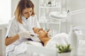 Young cosmetologist or dermatologist making ultrasound facial cleaning for woman in beauty salon Royalty Free Stock Photo