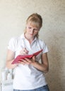 a young cosmetologist girl in a white T-shirt writes in a pink notebook Royalty Free Stock Photo