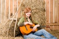 Young country woman play guitar in barn