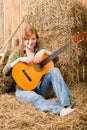 Young country woman sitting on hay with guitar