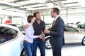 Young couple is advised by the seller at the car dealership Royalty Free Stock Photo