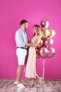 Young couple with air balloons near wall