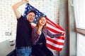 Young couple with an American flag smiling indoors. Royalty Free Stock Photo