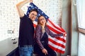 Young couple with an American flag smiling indoors. Royalty Free Stock Photo