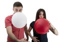 Young couple announcing their baby while blowing balloons