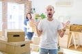 Young couple arround cardboard boxes moving to a new house, bald man standing at home celebrating crazy and amazed for success Royalty Free Stock Photo