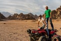 Young couple on ATV quad bike with traditional bedouin head scarfs in desert Royalty Free Stock Photo