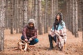 Couple in the forest. A girl is sitting covered in a blanket, the guy sharpens wooden knives. Royalty Free Stock Photo