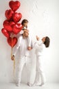 A young couple with a baby and red heart-shaped balloons on Valentine's day Royalty Free Stock Photo