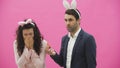 Young couple are beautiful on pink background. During this time they are dressed in rabble ears. Looking at each other