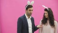 Young couple are beautiful on pink background. During this time, they are dressed in rabble ears. Looking at each other