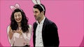 Young couple are beautiful on pink background. During this time, they are dressed in rabble ears. Looking at each other