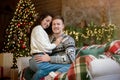 Young couple beautiful woman and handsome man both wearing warm sweaters hugging on sofa in room decorated for