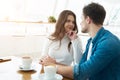 Young couple beautiful woman and handsome man drinking coffee in cafe looking at each other, love and tenderness concept