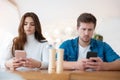 Young couple beautiful woman and handsome man sitting at cafe during coffee break, both holding smartphones, digital influence