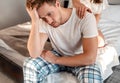 Young couple in the bed. Close-up of unhappy man is sitting on the edge of bed, problem in the bedroom