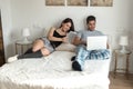 Young couple in bed entertained on their computer and tablet Royalty Free Stock Photo