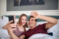 A young couple in the bed at the hotel room enjoying taking selfies. Couple  love  hotel  together Royalty Free Stock Photo