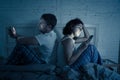 Couple in bed on mobile phones ignoring each other in relationship problems and technology addiction Royalty Free Stock Photo