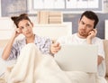 Young couple in bed man working woman bored Royalty Free Stock Photo