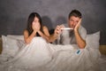 Young couple in bed scared and stressed after positive result on pregnancy test with pregnant woman expecting unwanted baby and ma Royalty Free Stock Photo