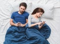 Young couple in bed top view morning concept phone addicted