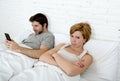 young couple in bed unsatisfied wife frustrated while internet addict husband is using mobile phone social network obsession