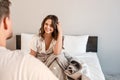 Young couple in the bed. Smiling beautiful hungry woman is waiting for delicious breakfast in the morning