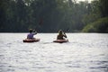 Young couple from behind kayaking together on lake during a summer day