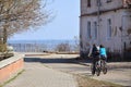 A young couple of bikers ride through empty streets during clear weather. The guy and the girl go on bicycle