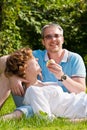 Young couple bites apple, sitting on a grass