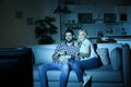 Young couple with bowl of popcorn watching TV on sofa