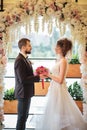 Young couple, bride and groom near arch. Wedding decor large wreath of flowers