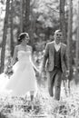 young couple bride in a white short dress and groom in a gray suit in a pine forest