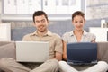 Young couple browsing internet at home smiling Royalty Free Stock Photo