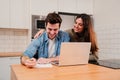 Young couple browsing on internet using a laptop searching a mortgage and calculating their budget sitting at home Royalty Free Stock Photo