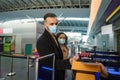 Young couple of business partners in protective medical masks, standing at the check-in counter while waiting for check-in, Royalty Free Stock Photo
