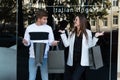 Young couple buyers with shopping bags over shop window background. Guy look at his girlfriend in surprise. Black Friday