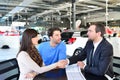 young couple buying a new car in the showroom of a car dealership - signature sales contract with seller Royalty Free Stock Photo