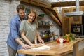 Young couple caking pizza in kitchen together