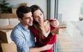 Young couple with cardboard boxes moving in a new home, looking out of window.